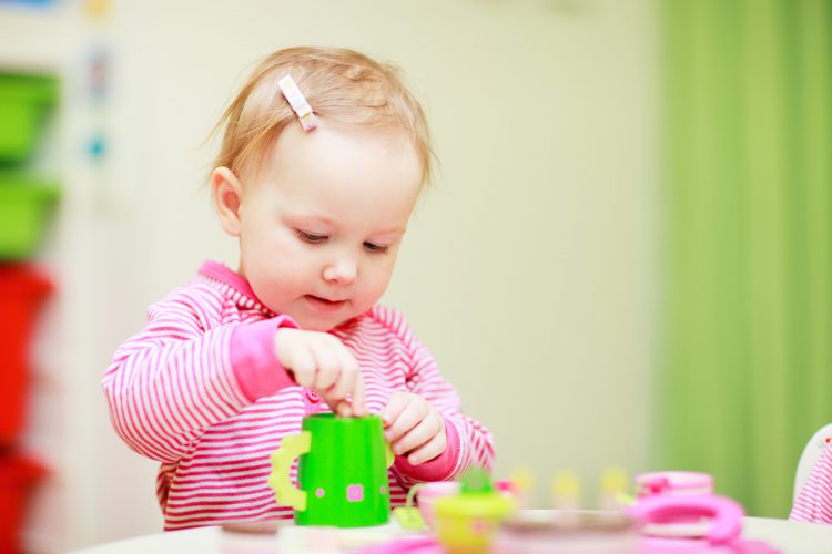 Adorable little girl playing with toys in her room