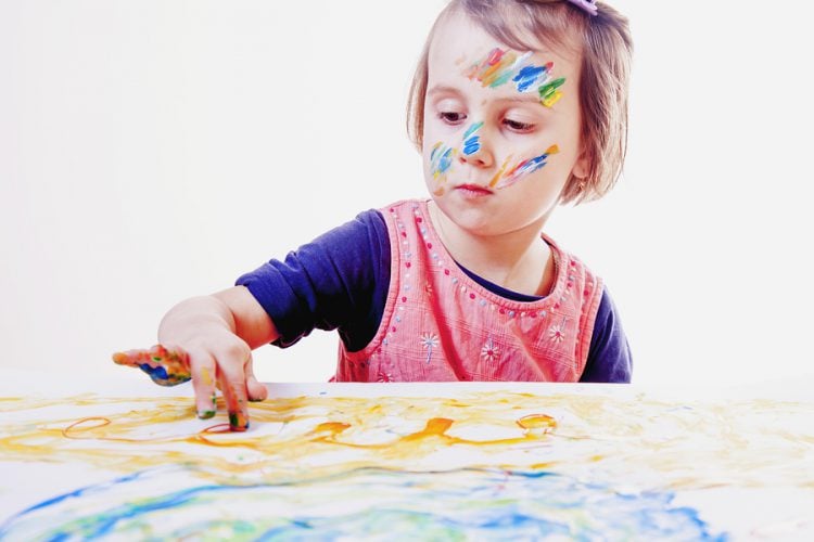 Little cute child girl painting on a white wall background (Creativity, education, child development in art, happy childhood, abilities concept)